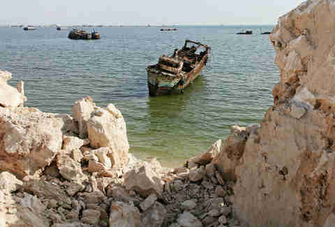rusted ship in front of rocks