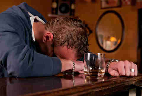Man passed out at a bar surrounded by drinks