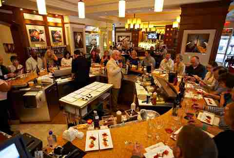 Round table of diners enjoying a tasting paired with wine with host