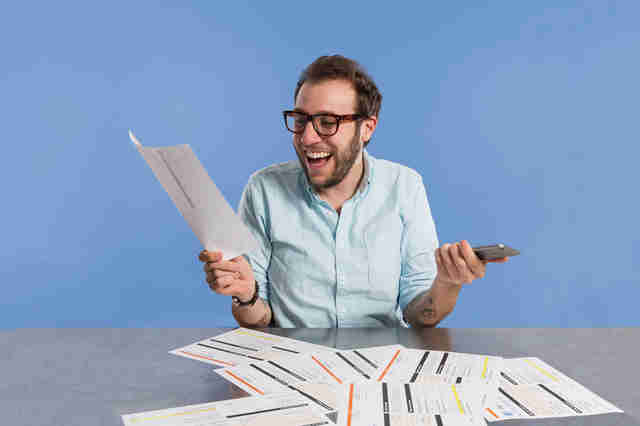 man looking happy with iPhone in hand and phone bill in other hand