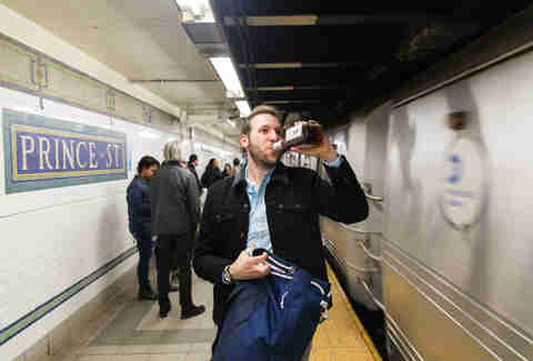 Man drinking whiskey as NYC subway passes