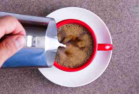 milk being poured into coffee mug