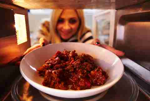 Woman putting leftovers in microwave