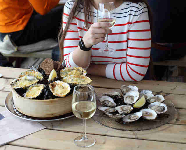 Woman eating oysters and drinking white wine