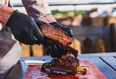 Chef holding cutted juicy slow cooked meat in hands