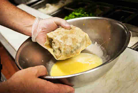 The tortilla is folded up and dipped in an egg wash before its deep fried.