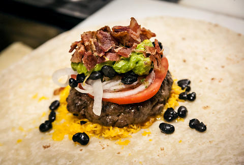 Crumbled bacon is added to the Supreme Nacho Burger at Slater's 50/50 in Liberty Station San Diego.