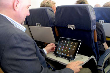 man using ipad on plane