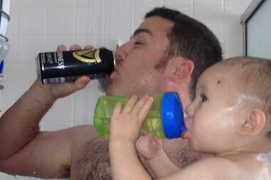 Father drinking beer in shower with baby son