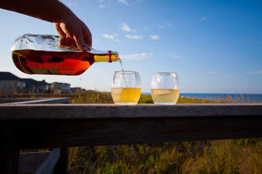 Person pouring wine into two glasses