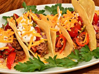 Beef, cheese, and tomato tacos lined up on a plate