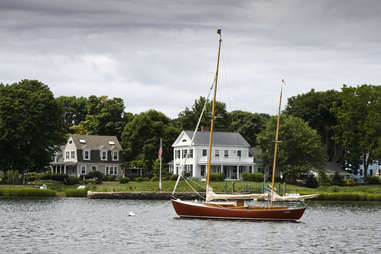 a sailboat on a lake near colonial houses