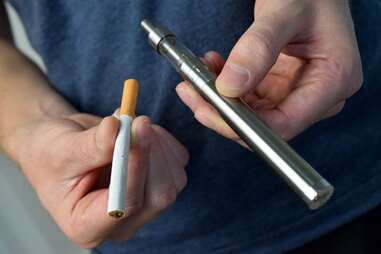 hands holding a cigarette and vape pen