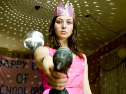 The Loved Ones actress stands threateningly with a power drill in a pink dress and crown