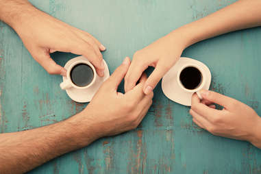 Couple holding hands over cups of coffee