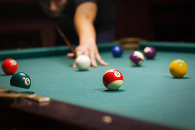 Person playing shooting cue ball in a game of pool