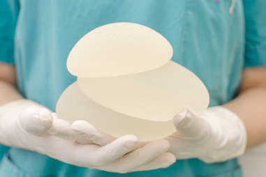 Doctor in scrubs holding breast implants