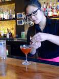 D.C. bartender fixing garnish on orange cocktail
