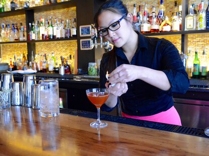 D.C. bartender fixing garnish on orange cocktail