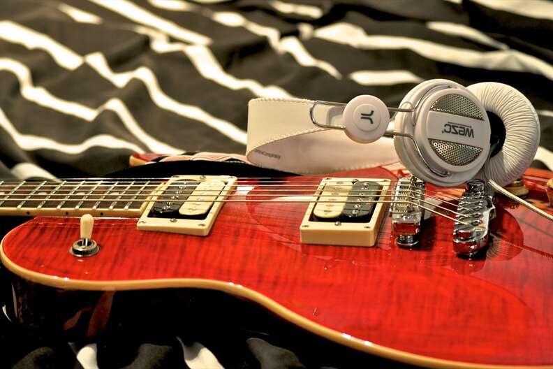 guitar and headphones lying on bed