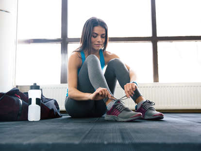 woman lacing up sneakers at gym