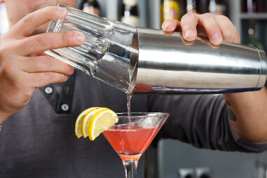 Mixologist finishing pink drink with lemon wedges