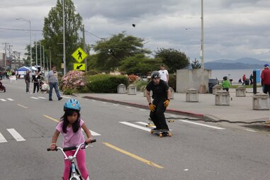 little girl riding a bike and a skateboarder at Alki