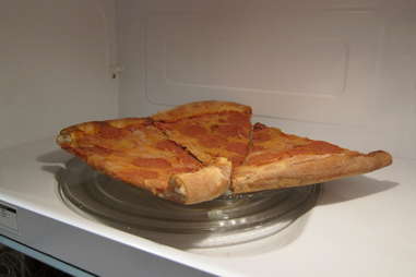 Frozen pizza being reheated in microwave