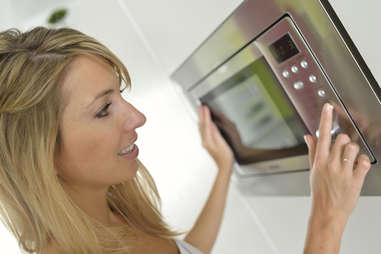 Girl pressing buttons on microwave