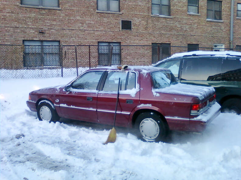 Red car warming up in snowy parking lot