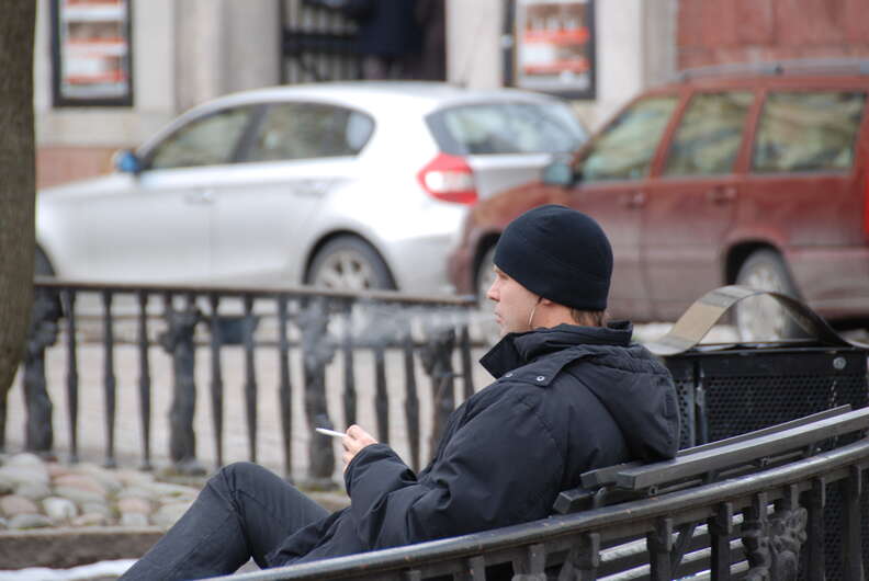 Man smoking cigarette on park bench