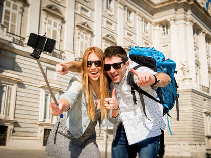 man and woman using selfie stick on vacation