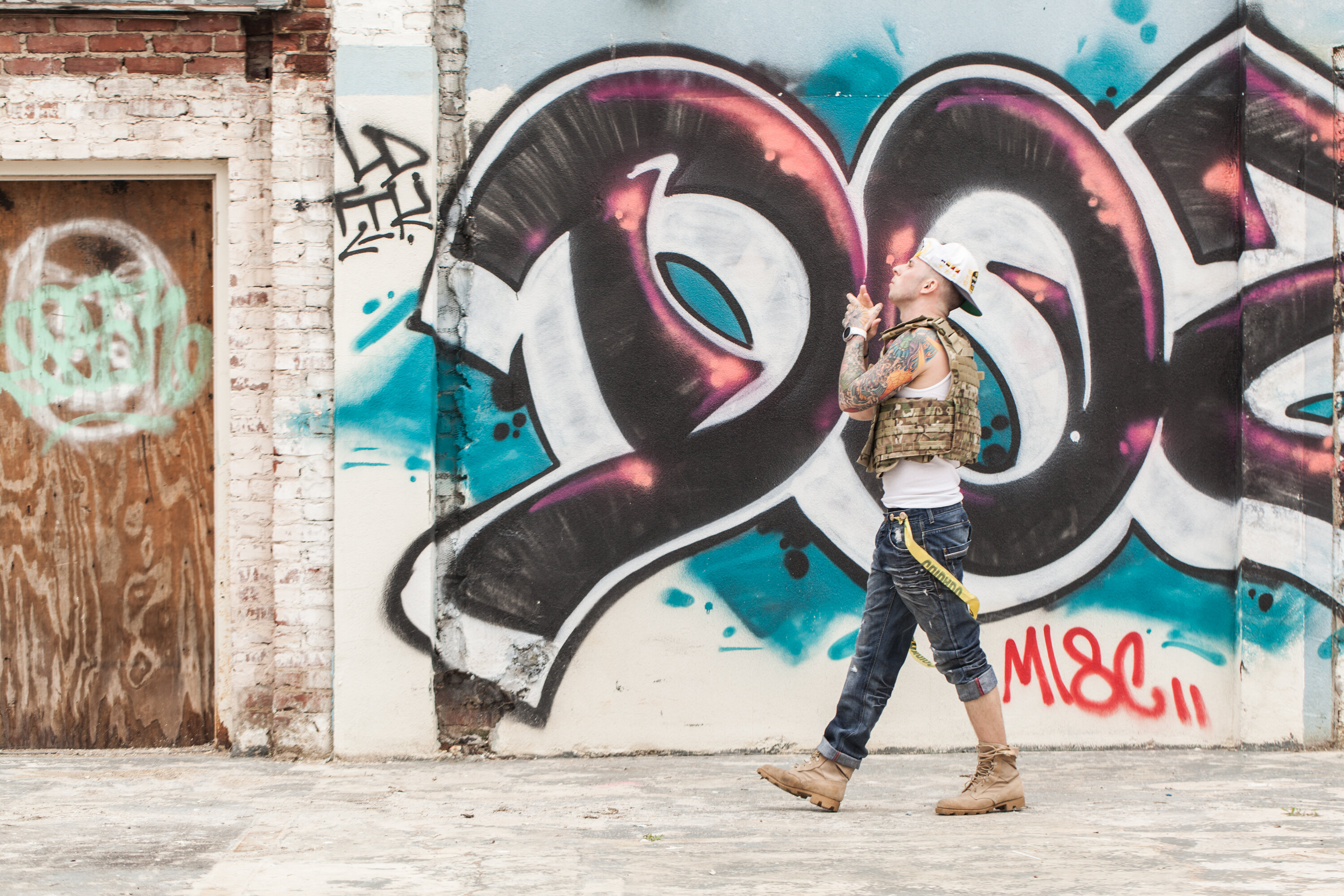 Portrait of rapper Anthony Bunch walking near graffiti wall