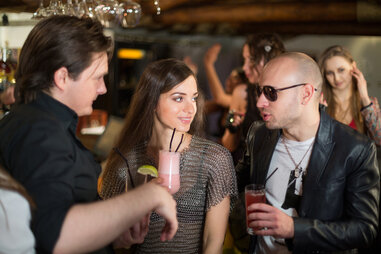 man in leather jacket talking to woman at a bar