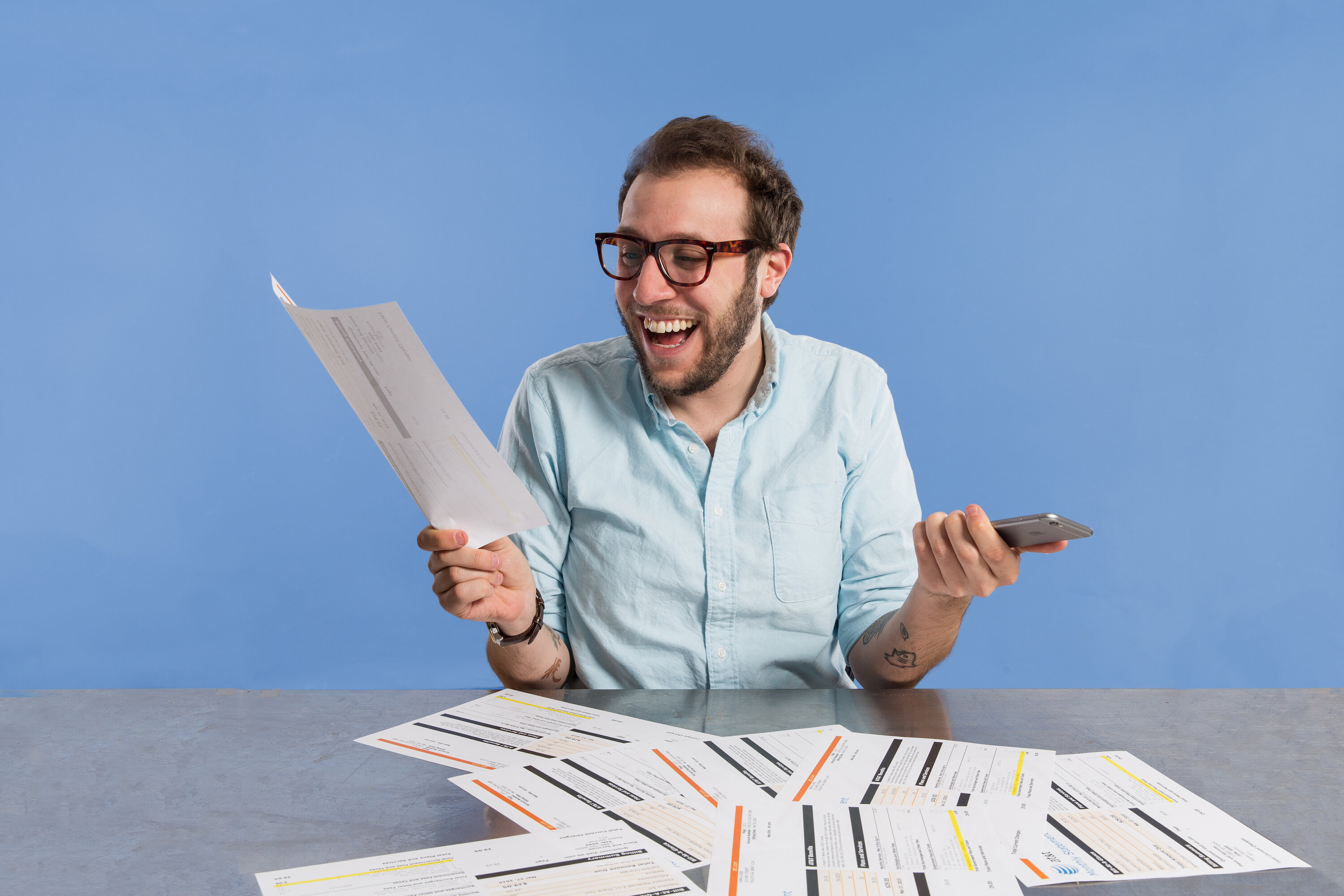 man looking happy with iPhone in hand and phone bill in other hand