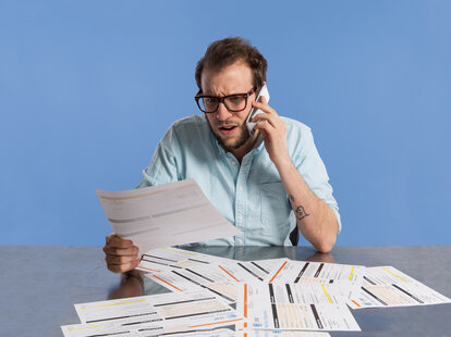 man talking on iphone 6 while looking at a phone bill