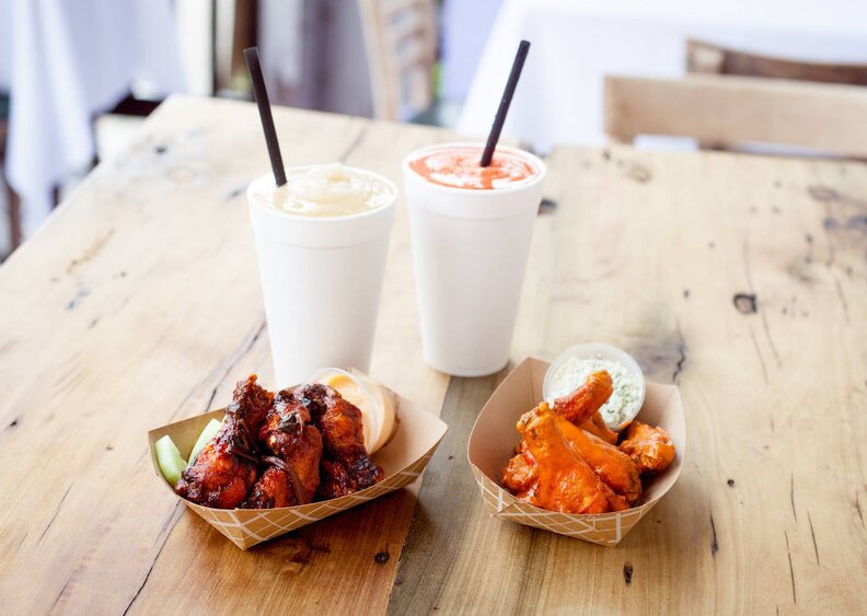 Beverages and small paper containers of barbecued chicken