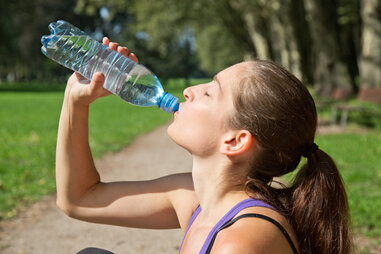 woman drinking water after working out