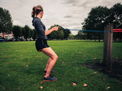 woman exercising outside with a resistance band