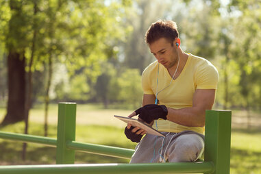 man working out outside with tablet