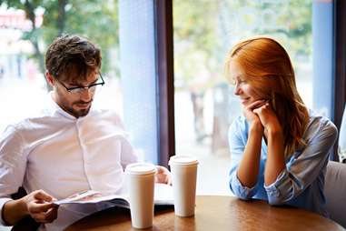 couple in a cafe man reading while woman looks on
