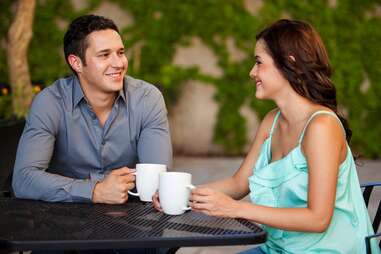 Couple drinking coffee and smiling on their first date at a restaurant