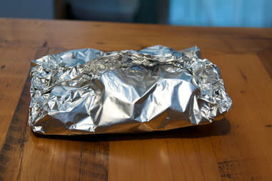 Item wrapped in aluminum foil placed on table