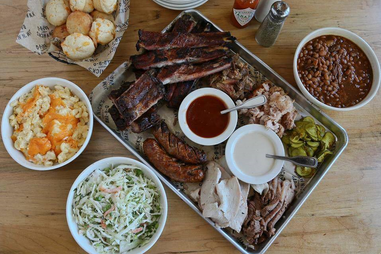 Sausage, brisket, and BBQ sauces on a metal platter