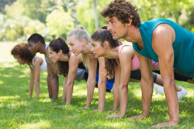 group of people doing push-ups outside