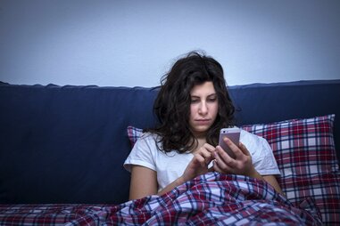 Girl using smartphone in bed at night