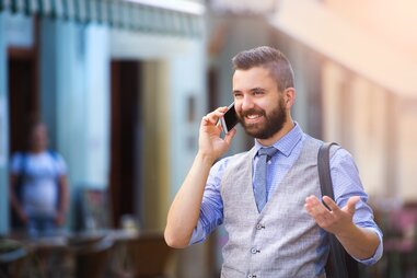 a well dressed man talking on the phone in a city