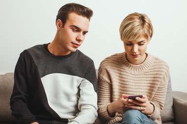 jealous guy looking over at his girlfriend's phone