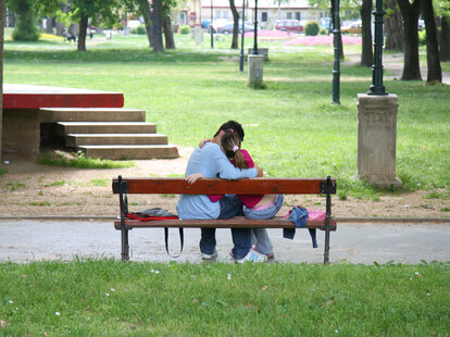 couple kissing on a bench outside