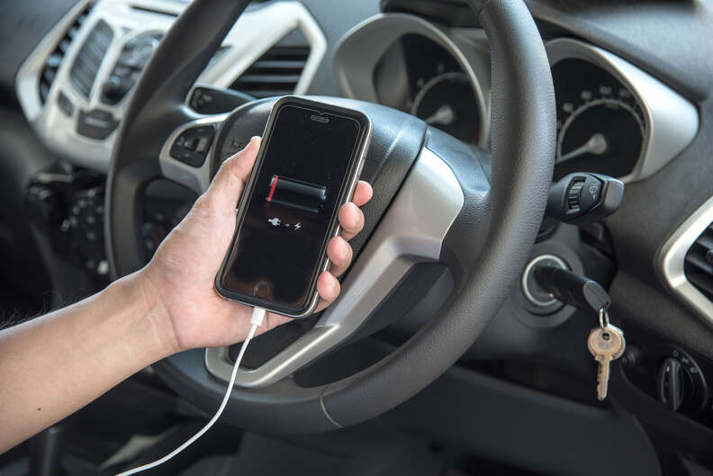 man charging dead iphone in car
